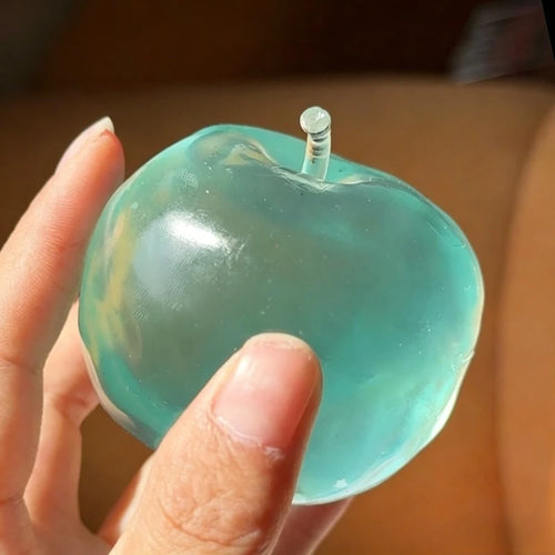 Translucent blue apple moldable squishy being squeezed in a hand