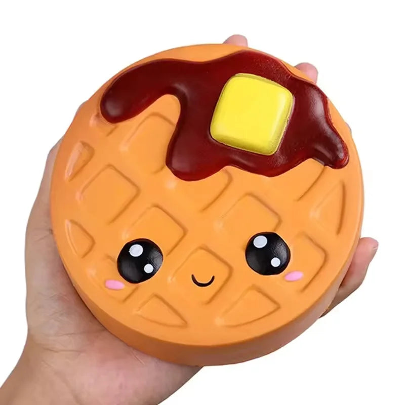 Jumbo scented waffle squishy with syrup, a butter pat and a smiling face held in a hand