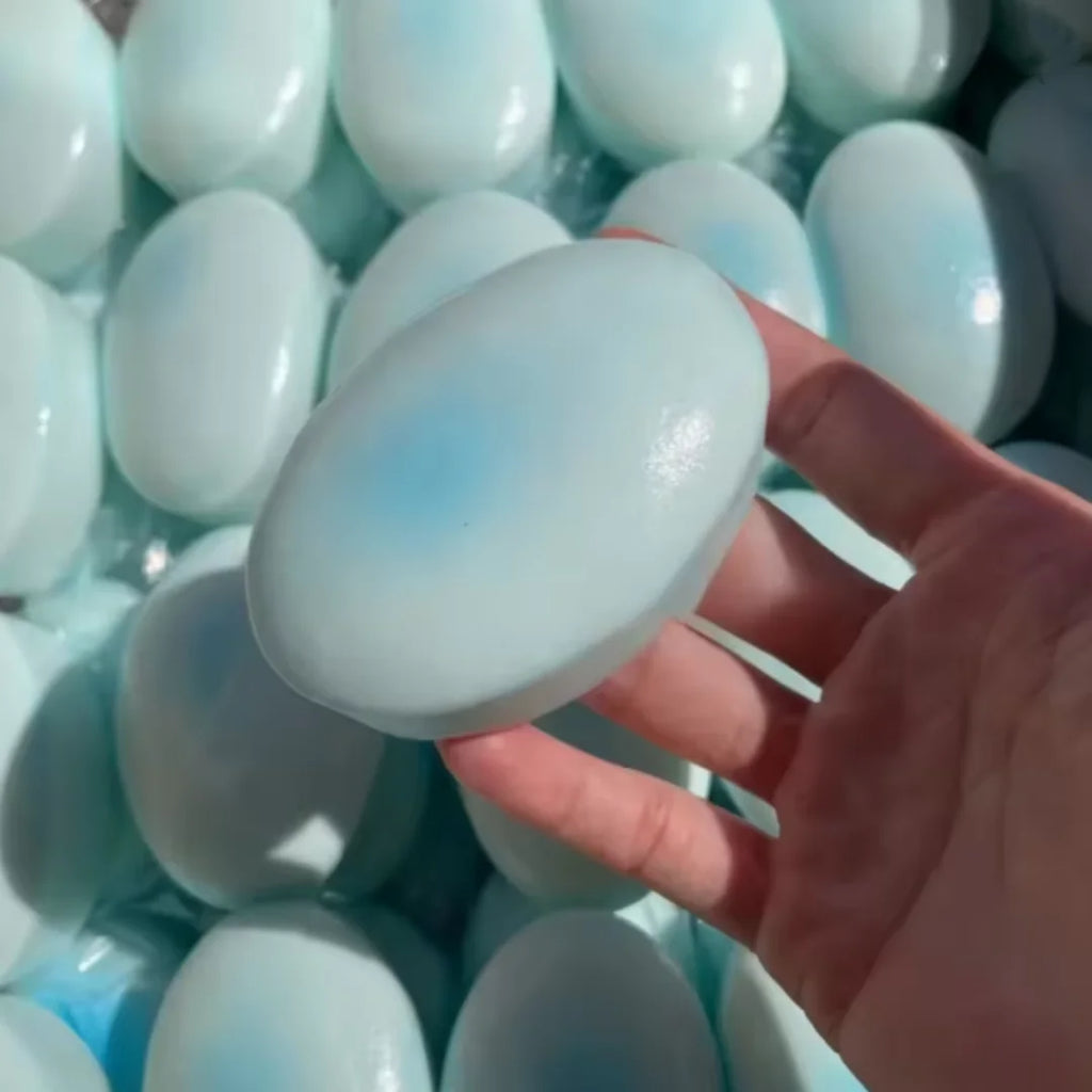 Pale blue cheese cake squishy being pressed flat in a hand